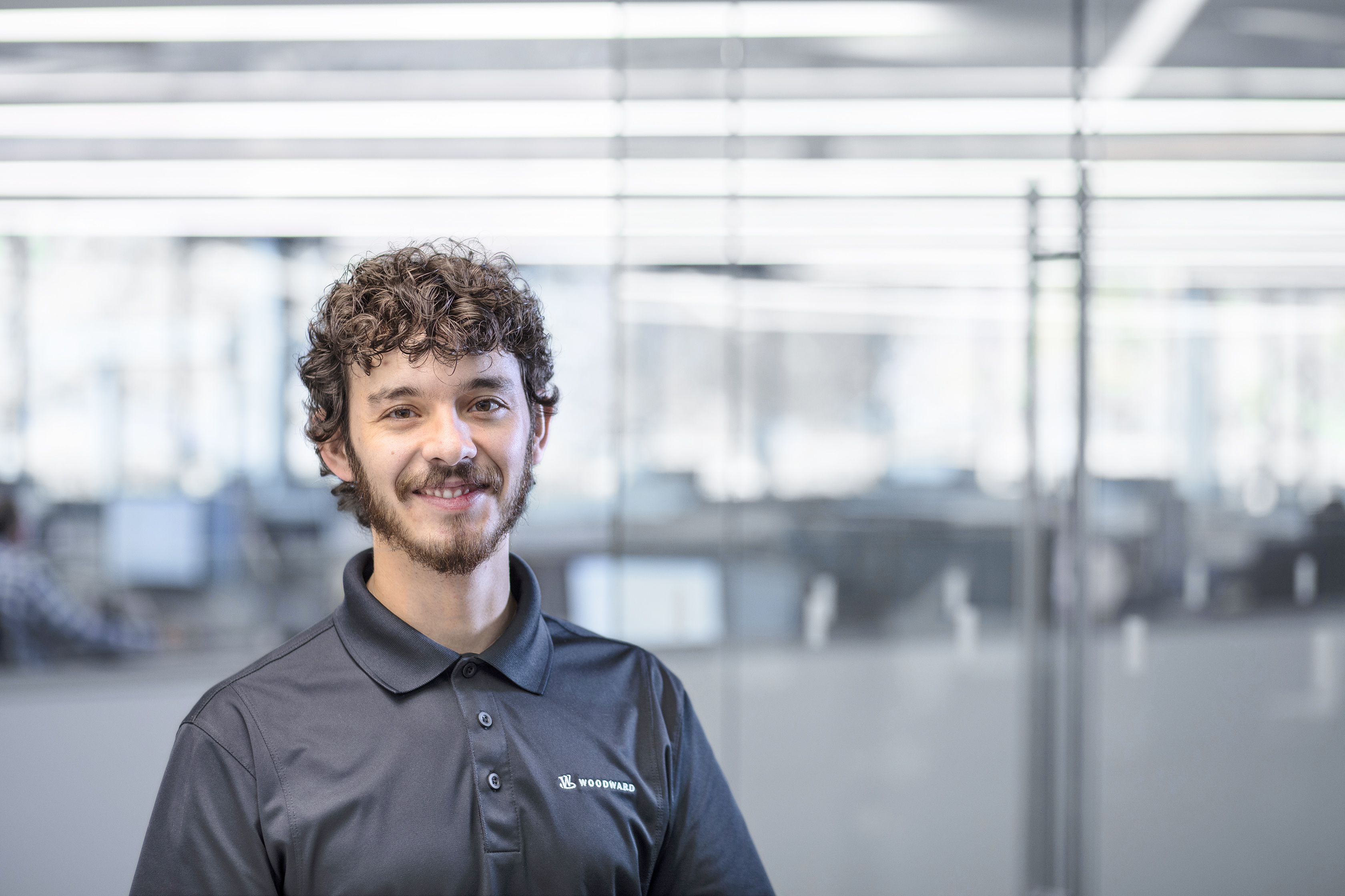 Male with curly hair and beard smiling